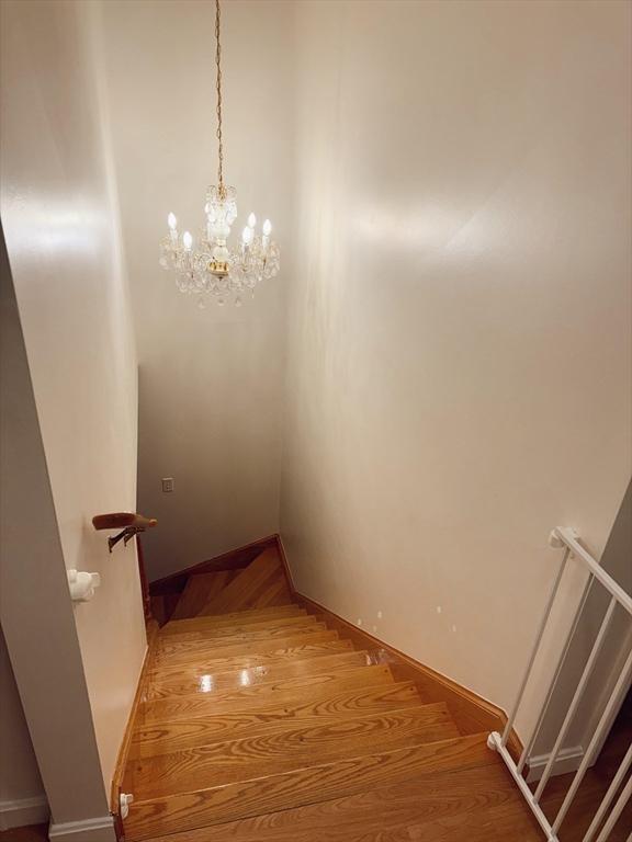 stairway featuring wood-type flooring and a chandelier