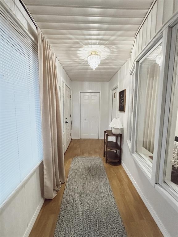 hall featuring light wood-type flooring and a notable chandelier