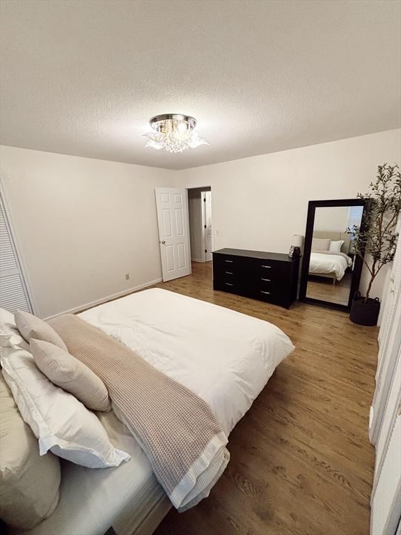 bedroom with a textured ceiling and dark hardwood / wood-style floors