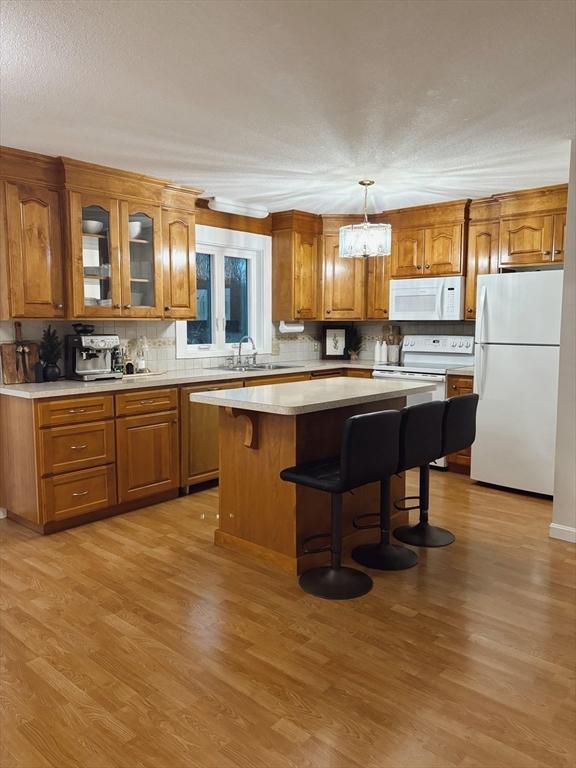 kitchen featuring a center island, light hardwood / wood-style floors, white appliances, and sink