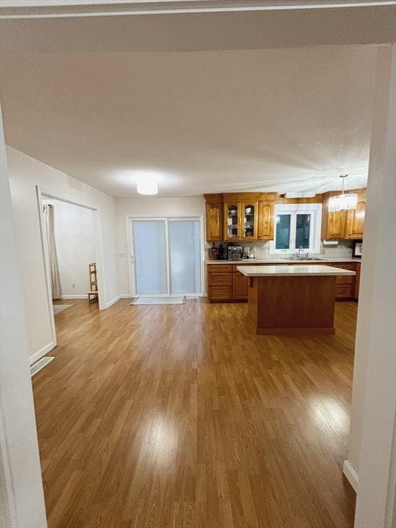 kitchen with decorative backsplash, a kitchen island, decorative light fixtures, and hardwood / wood-style flooring