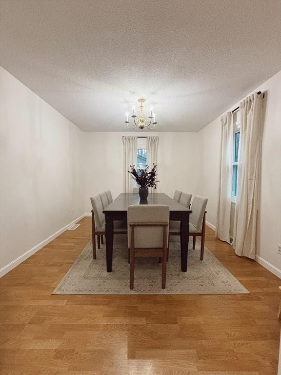 dining room featuring hardwood / wood-style floors, a textured ceiling, and an inviting chandelier