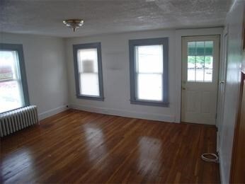 interior space with radiator heating unit, a textured ceiling, and dark wood-type flooring