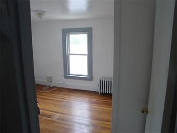 spare room with radiator heating unit and wood-type flooring