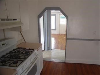 kitchen with white range with gas stovetop, white cabinetry, dark wood-type flooring, and range hood