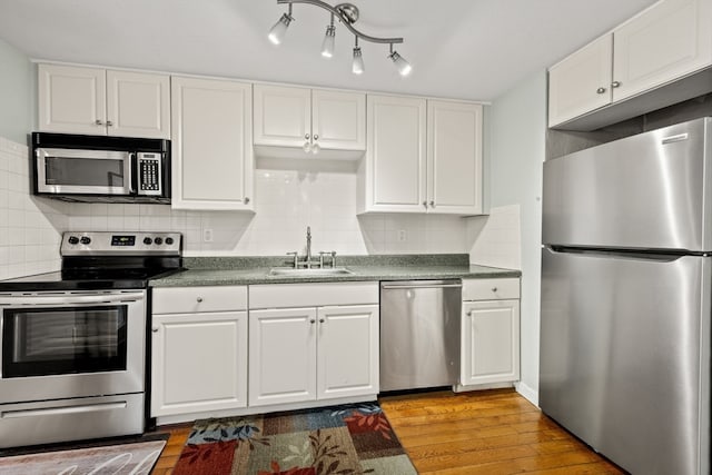 kitchen with light hardwood / wood-style floors, sink, appliances with stainless steel finishes, and tasteful backsplash