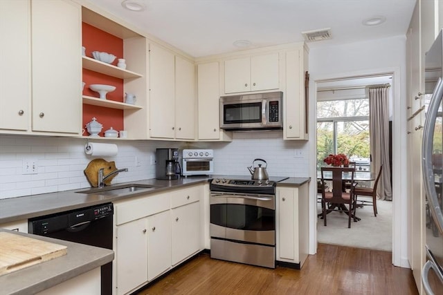 303 Goddard Ave Unit 303, Brookline, MA 02445 - kitchen with appliances with stainless steel finishes, open shelves, a sink, wood finished floors, and decorative backsplash