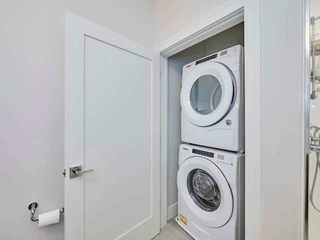 clothes washing area with stacked washing maching and dryer