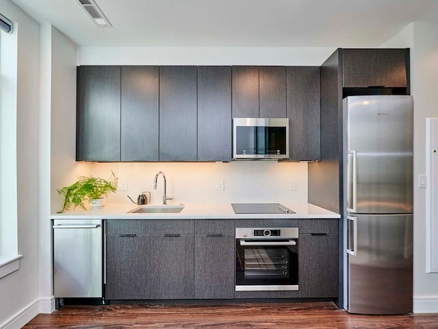 kitchen with appliances with stainless steel finishes, dark wood-type flooring, and sink