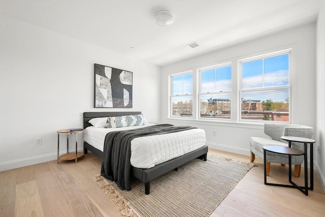 bedroom featuring light wood-style flooring, baseboards, and visible vents