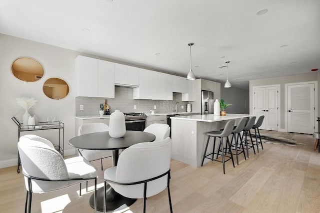 kitchen featuring backsplash, a kitchen island, light countertops, light wood-style flooring, and stainless steel appliances