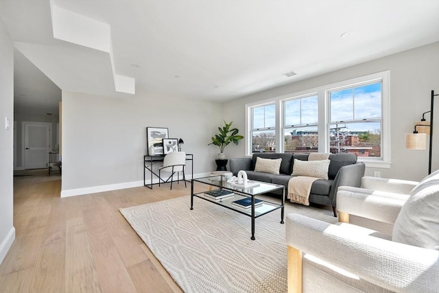 living room featuring visible vents, baseboards, and light wood-style flooring