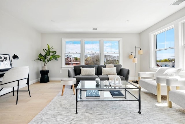 living room featuring light wood-style flooring, baseboards, and visible vents