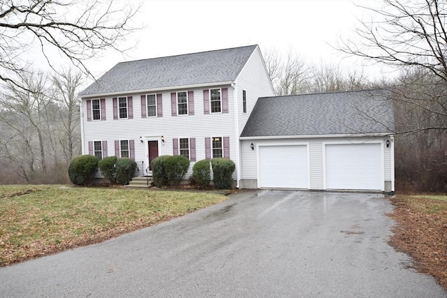 colonial inspired home featuring a front lawn and a garage