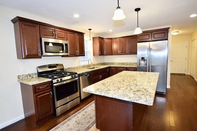 kitchen with appliances with stainless steel finishes, dark hardwood / wood-style flooring, a kitchen island, and hanging light fixtures