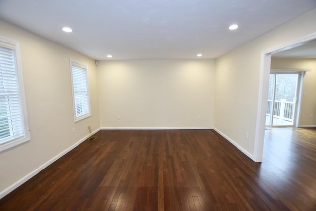 spare room with plenty of natural light and dark wood-type flooring