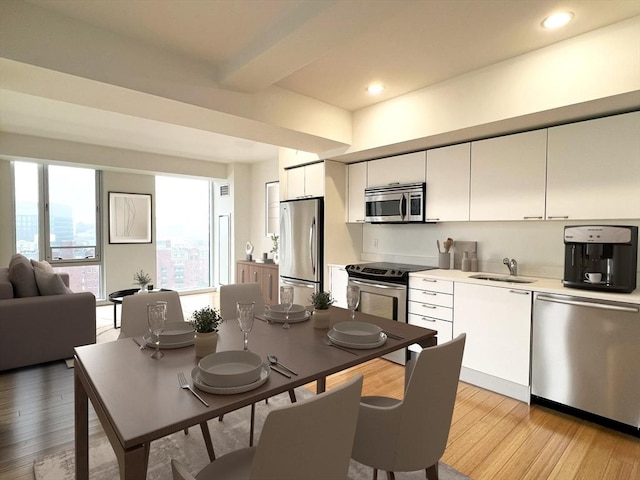 2 Earhart St Unit Ph6, Cambridge, MA 02141 - kitchen featuring appliances with stainless steel finishes, a sink, white cabinets, light countertops, and light wood-type flooring