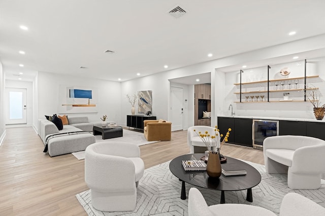 living room with beverage cooler, light hardwood / wood-style floors, and sink