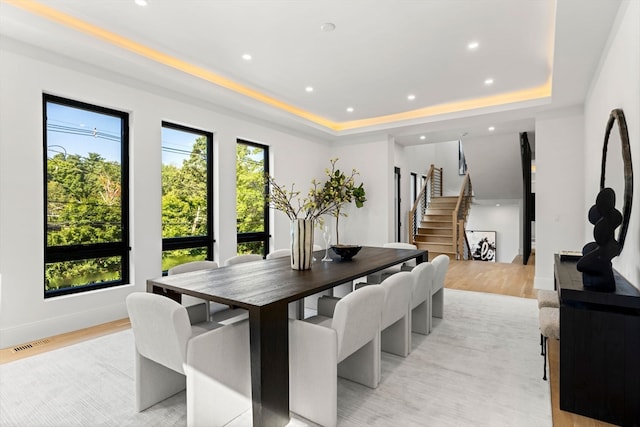 dining area with light hardwood / wood-style flooring and a tray ceiling