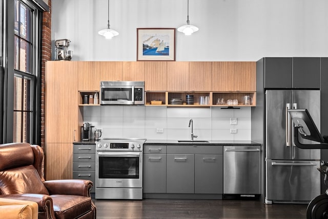 kitchen featuring gray cabinetry, sink, stainless steel appliances, pendant lighting, and dark wood-type flooring