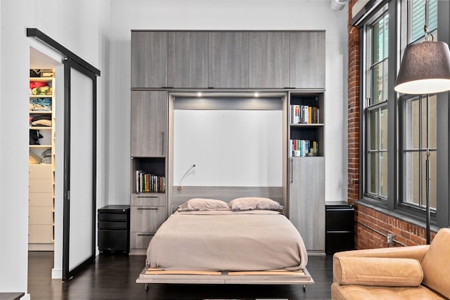 bedroom featuring brick wall and dark hardwood / wood-style flooring