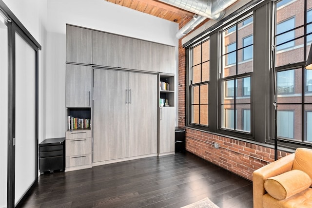 interior space featuring brick wall, dark wood-type flooring, and wooden ceiling