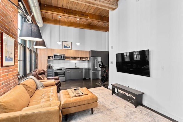 living room featuring beam ceiling, brick wall, sink, and wood ceiling