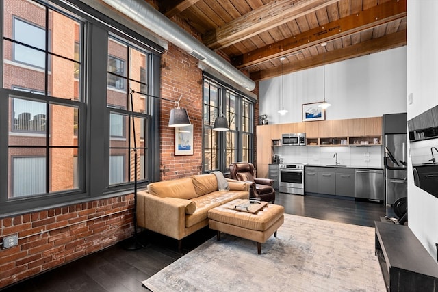 living room with a towering ceiling, wood ceiling, beamed ceiling, brick wall, and dark hardwood / wood-style floors