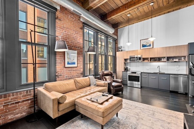 living room with wood ceiling, dark hardwood / wood-style flooring, a high ceiling, sink, and brick wall