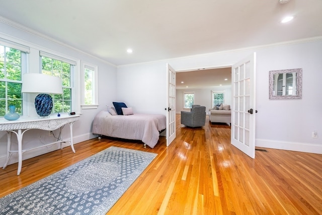 bedroom with multiple windows, french doors, and light wood-type flooring