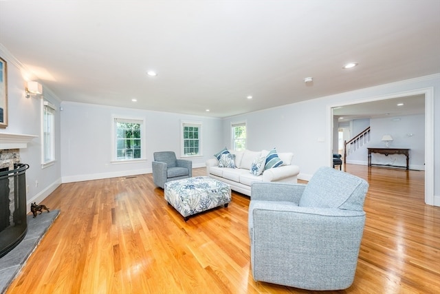 living room with a wealth of natural light, ornamental molding, and light hardwood / wood-style floors