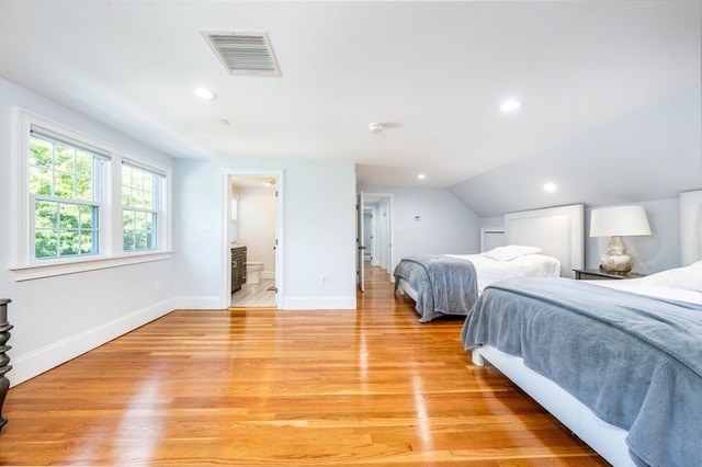 bedroom featuring ensuite bathroom, light wood-type flooring, and lofted ceiling