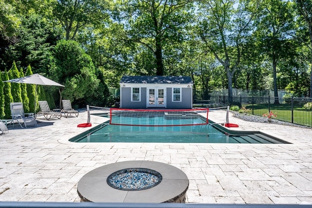 view of pool with a fire pit, a patio, and an outbuilding