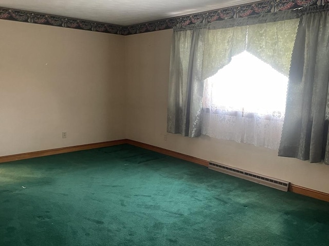 carpeted empty room featuring a baseboard heating unit