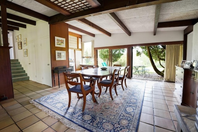 dining space featuring light tile patterned floors, stairway, and beamed ceiling