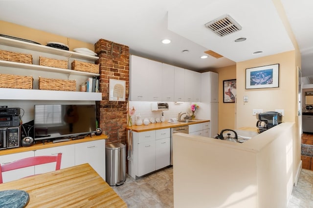 kitchen with butcher block counters, white cabinetry, sink, and tasteful backsplash