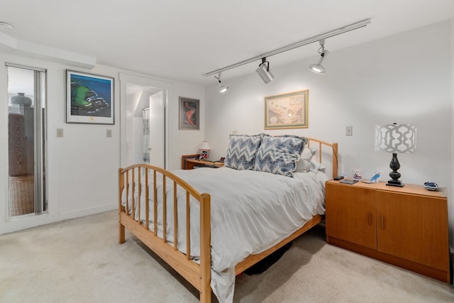 carpeted bedroom with track lighting and connected bathroom