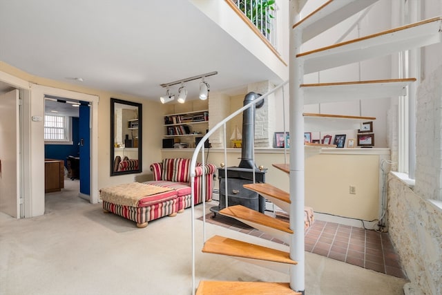 staircase with track lighting, carpet, and a wood stove