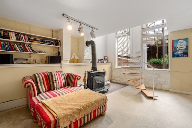 sitting room featuring a wood stove, track lighting, and carpet floors