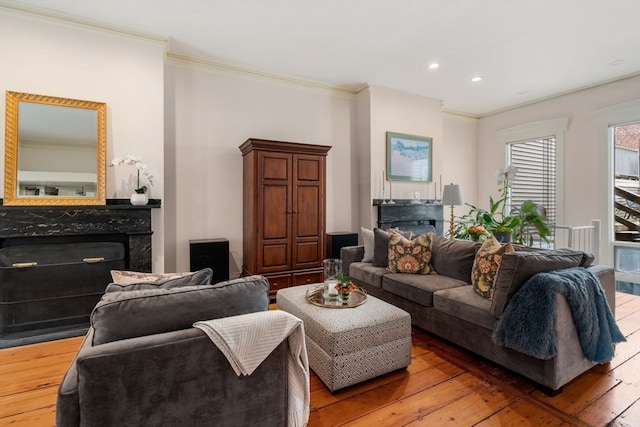 living room with wood-type flooring, crown molding, and a high end fireplace