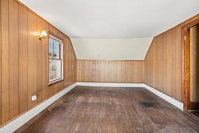 additional living space featuring dark wood-type flooring, visible vents, and wooden walls