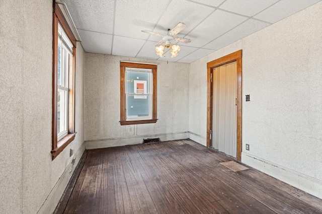 empty room with a paneled ceiling, ceiling fan, and hardwood / wood-style floors