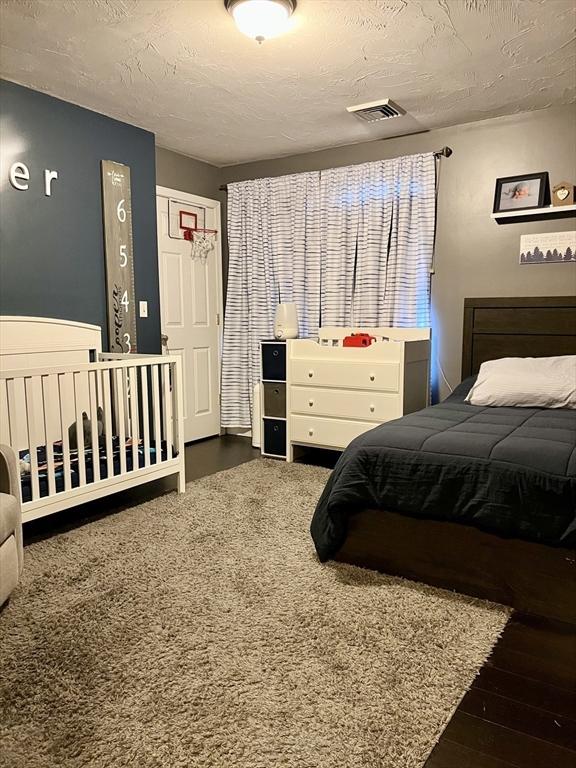 bedroom with dark wood-type flooring and a textured ceiling