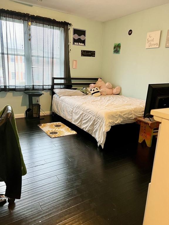 bedroom with multiple windows and dark hardwood / wood-style floors