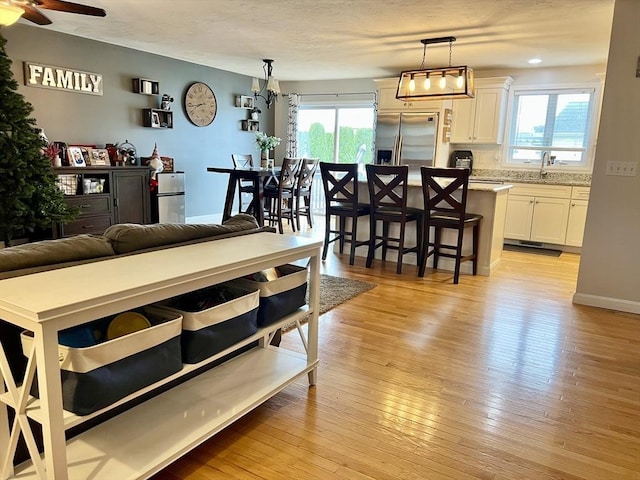 living room with sink, light wood-type flooring, plenty of natural light, and ceiling fan