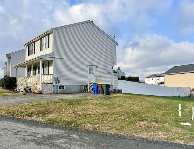 view of side of home featuring a yard and covered porch