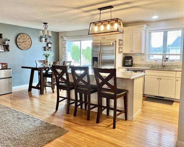 kitchen featuring white cabinets, stainless steel fridge, a kitchen island, and sink