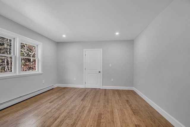 spare room featuring a baseboard heating unit and light wood-type flooring