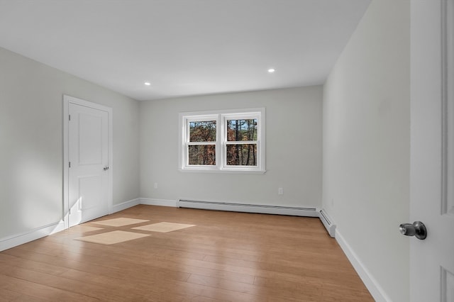 unfurnished room with baseboard heating and light hardwood / wood-style flooring