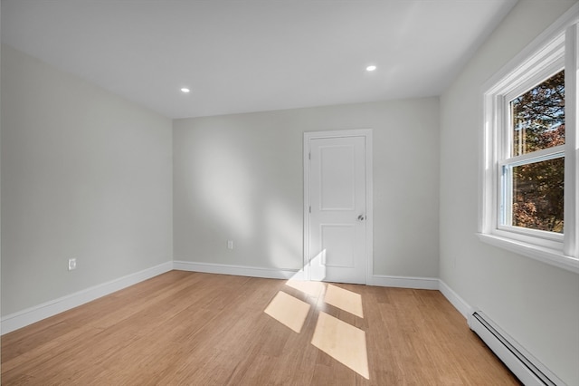 unfurnished room featuring light hardwood / wood-style floors and baseboard heating